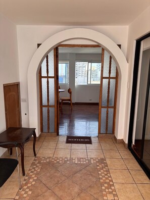 An arched doorway leading to a room with a tiled floor and a wooden table. - Carmen's House (Miraflores)