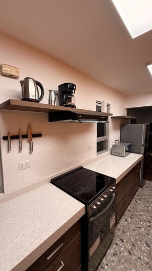 A modern kitchen with a built-in stove, a microwave, and a coffee maker on the countertop. - Carmen's House (Miraflores)
