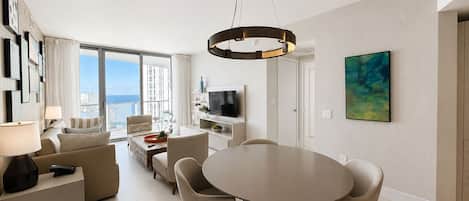 Una sala de estar moderna con comedor, ventanas amplias y vista al mar.