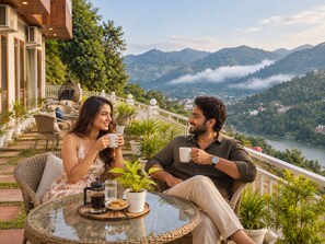 A couple seated at a table with a scenic view of mountains and a river.