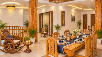 A dining area with a wooden table set for a meal, surrounded by wooden chairs.