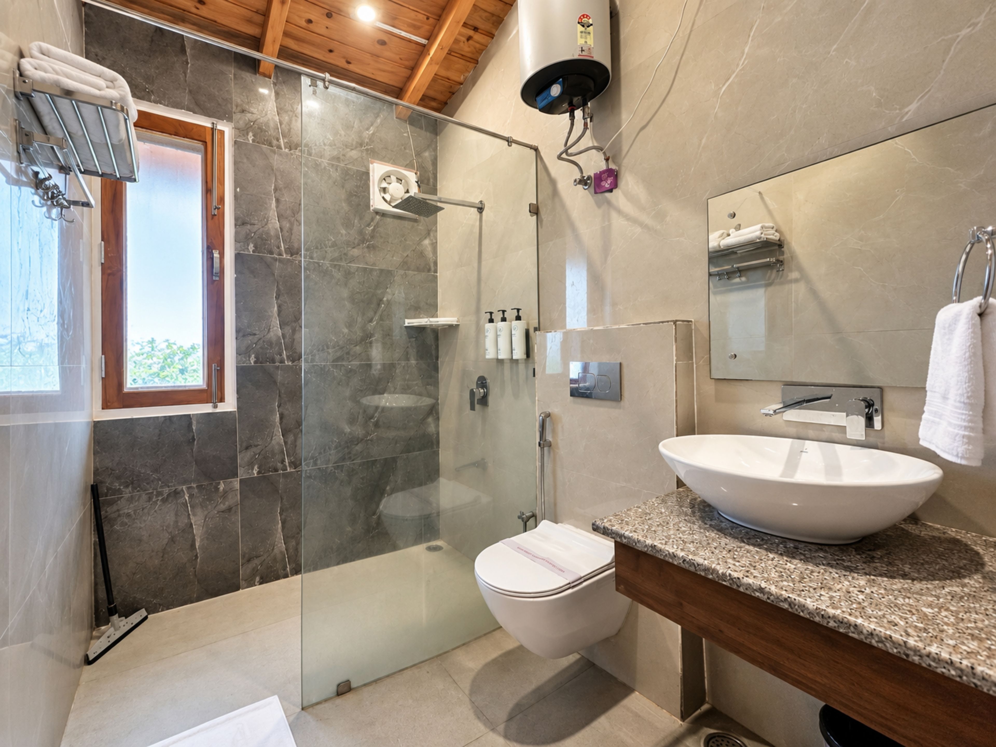 Un baño moderno con ducha envuelta en vidrio, lavabo blanco y un espejo grande.