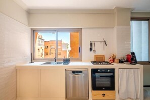 A compact kitchen with a built-in dishwasher, oven, and a window providing a view of the street. - Majorelle Retreat Marrakech City Center (Marrakech)