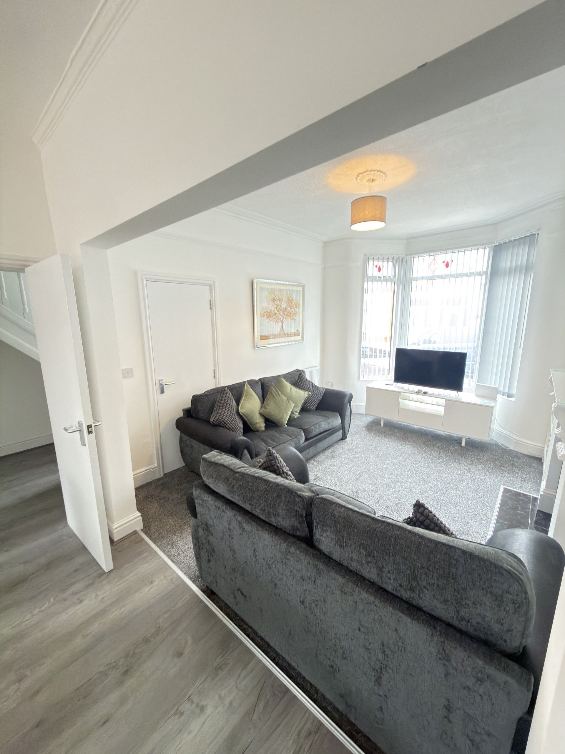 A living room with a grey sofa, a television, and a painting on the wall.