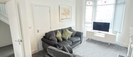 A living room with a grey sofa, a television, and a painting on the wall.