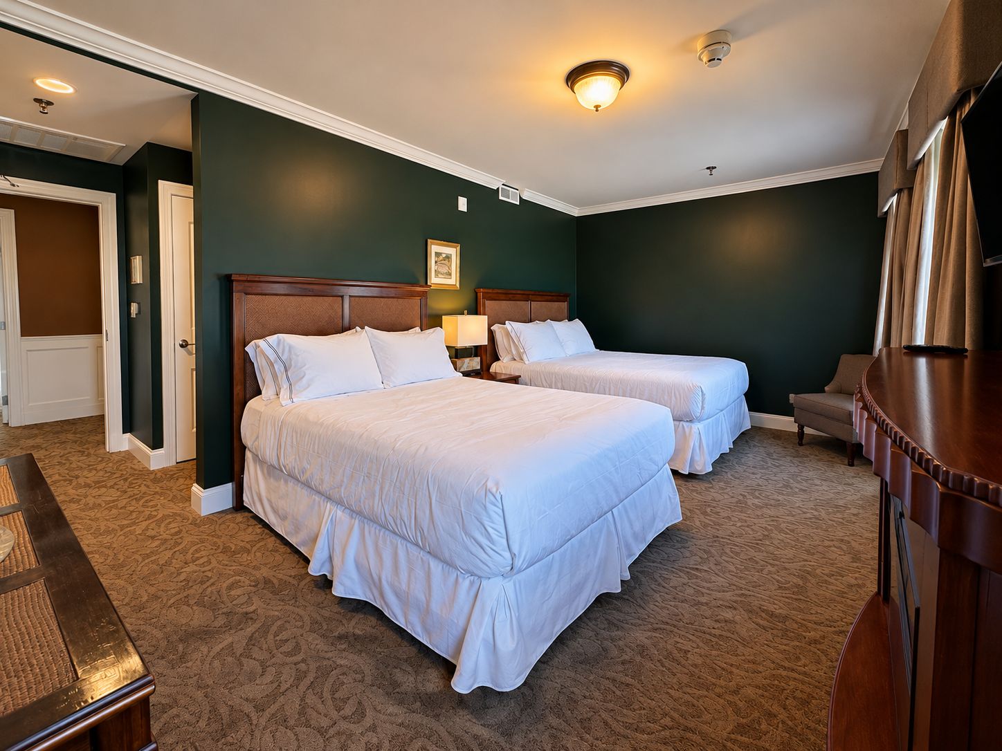 Ein Hotelzimmer mit zwei Betten, einem Schreibtisch und einem Stuhl.