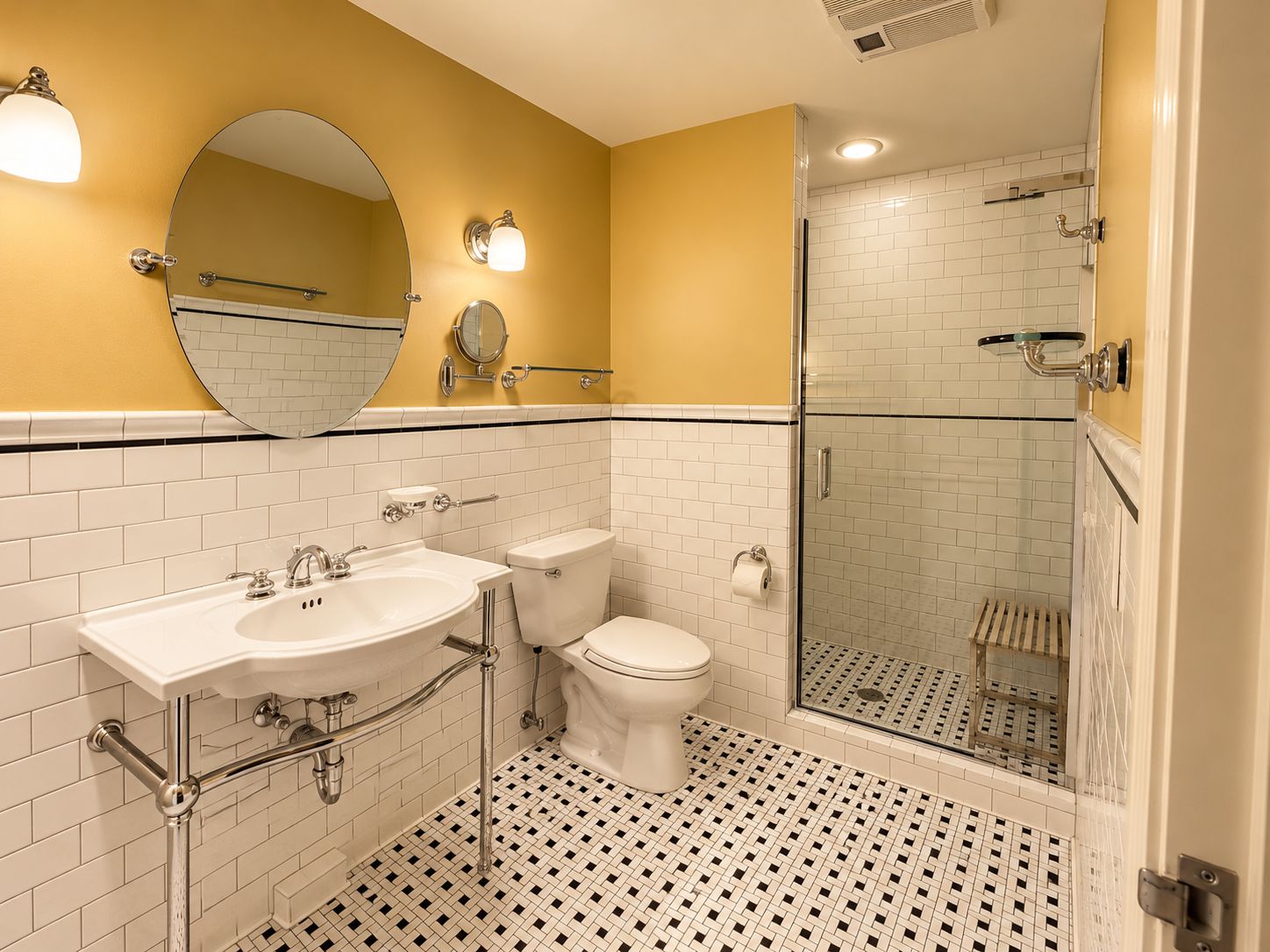 Un baño con lavamanos blanco, inodoro y zona de ducha con mampara de cristal.