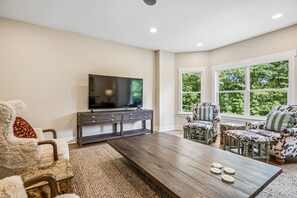 A living room with a flat-screen TV, dark wooden coffee table, and patterned furniture.