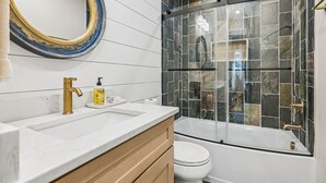 Un baño con lavamanos blanco, grifo dorado y un espejo grande con marco azul.