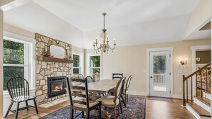 Un comedor con chimenea de piedra, un candelabro y vistas al exterior.