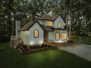 A two-story house with a front porch, a stone foundation, and a well-maintained lawn.