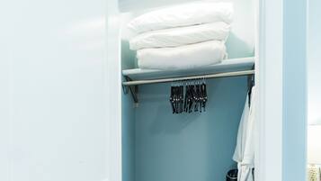 A bathroom with a blue wall, a towel rack with folded towels, a black radiator, and a white bath mat.