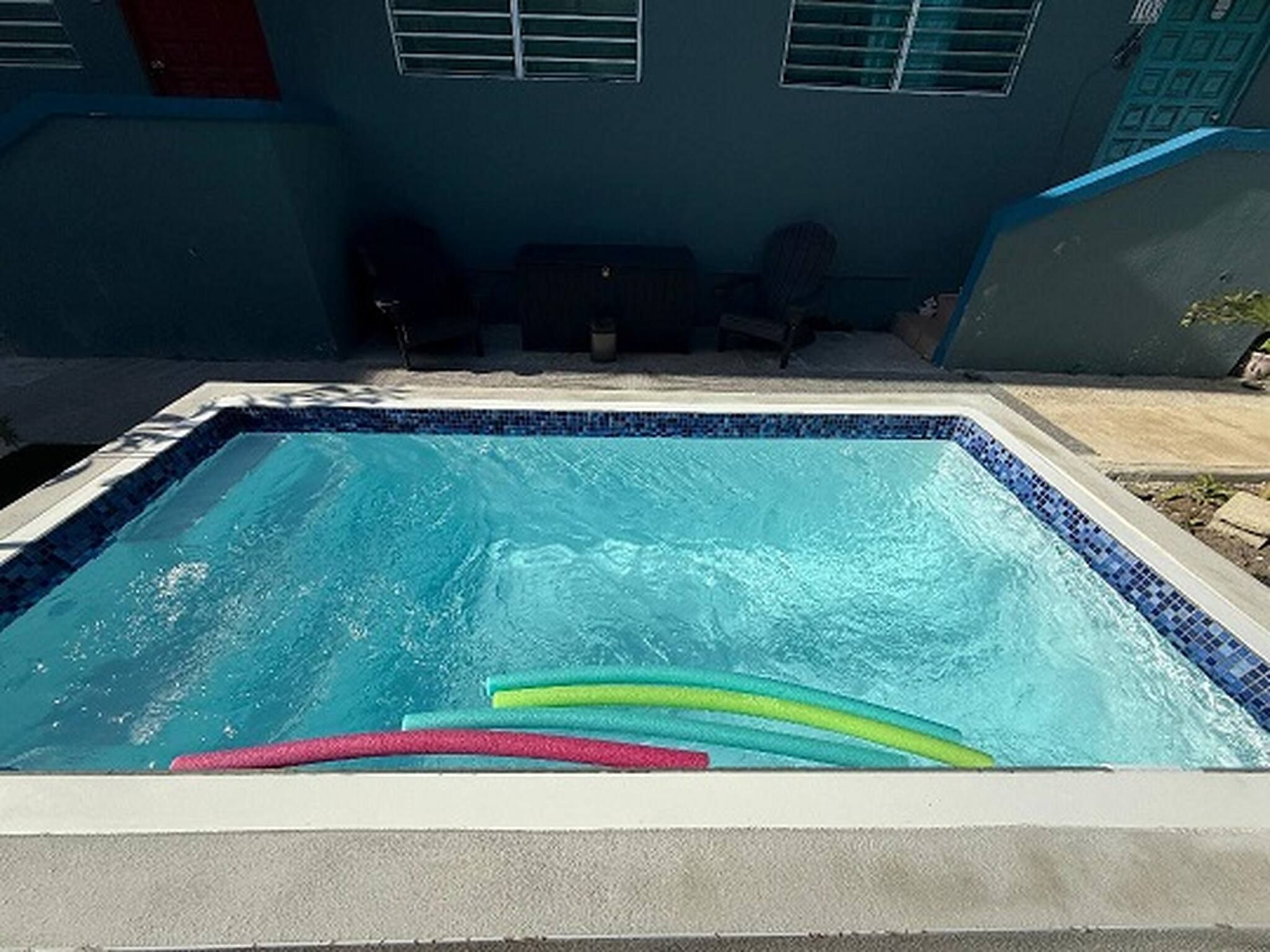 A rectangular swimming pool with a tiled edge, surrounded by a concrete deck.