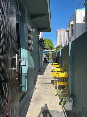 A narrow alleyway with a blue wall, a metal gate, and yellow chairs with potted plants. - 15 Minutes Airport, 10 Minutes Old San Juan, Private Patio and Share Pool (San Juan)