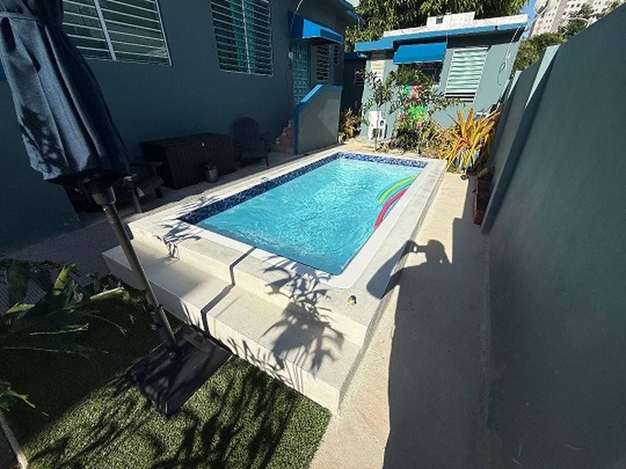 A rectangular swimming pool with a tiled edge, surrounded by a concrete deck.