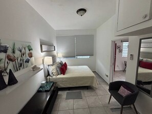A bedroom with a bed, bedside table, lamp, and a painting on the wall. - 15 Minutes Airport, 10 Minutes Old San Juan, Private Patio and Share Pool (San Juan)