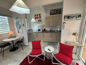 Un espace de vie compact comprenant un coin repas, une cuisine et un tapis rouge.