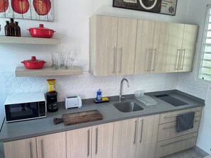Una cuina moderna amb armaris de fusta, microones, cafetera i un rentaplat.