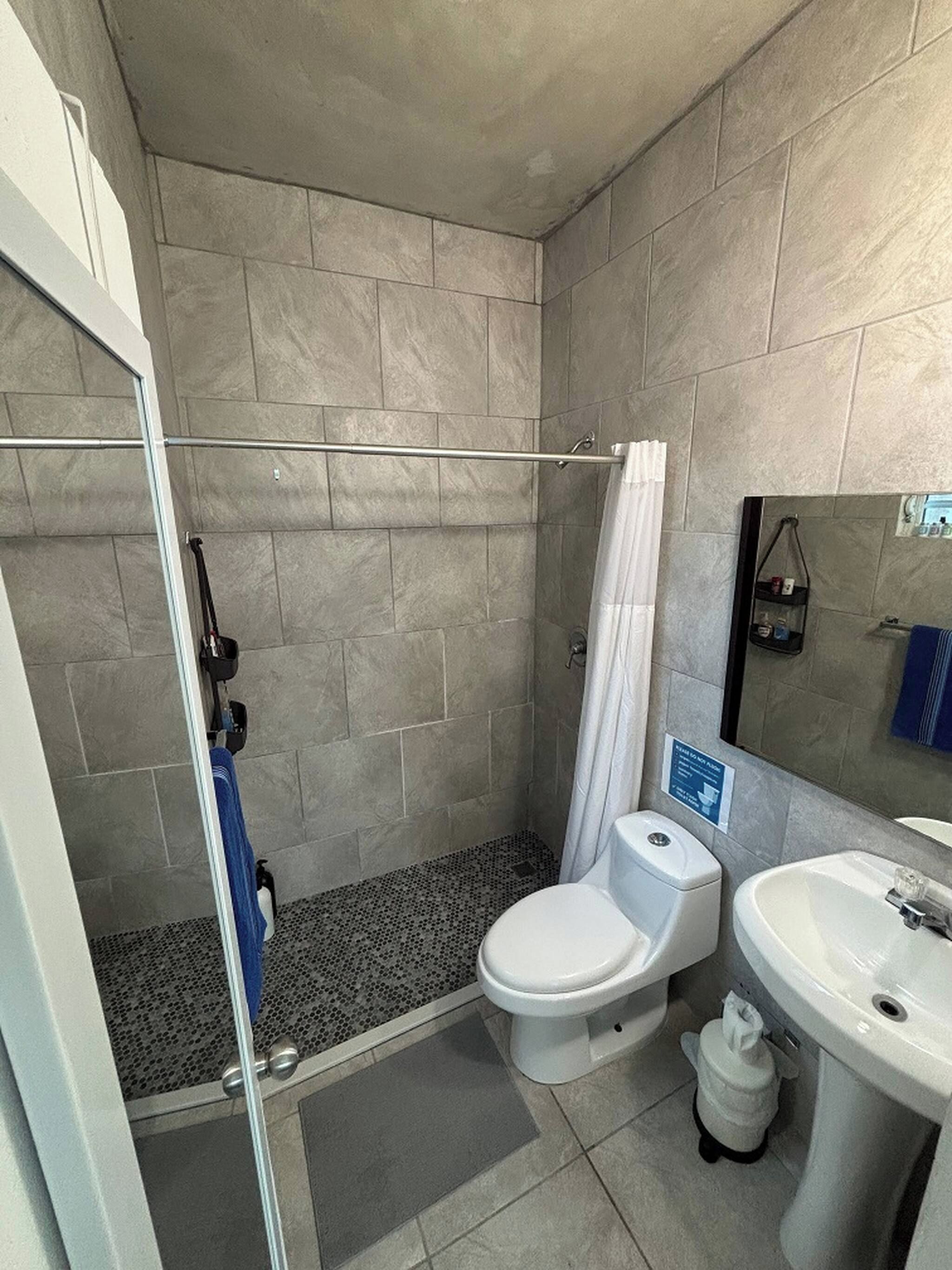 Een badkamer met douche, toilet en wastafel.