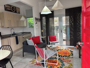 A compact living space with a kitchenette, a dining area, and a seating area with a colorful rug. - 15 Minutes Airport, 10 Minutes Old San Juan, Private Patio and Share Pool (San Juan)