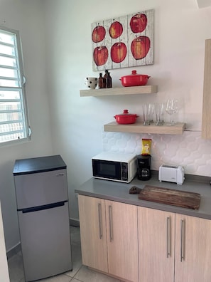 A compact kitchen with a refrigerator, microwave, toaster, and wooden cabinets. - 15 Minutes Airport, 10 Minutes Old San Juan, Private Patio and Share Pool (San Juan)