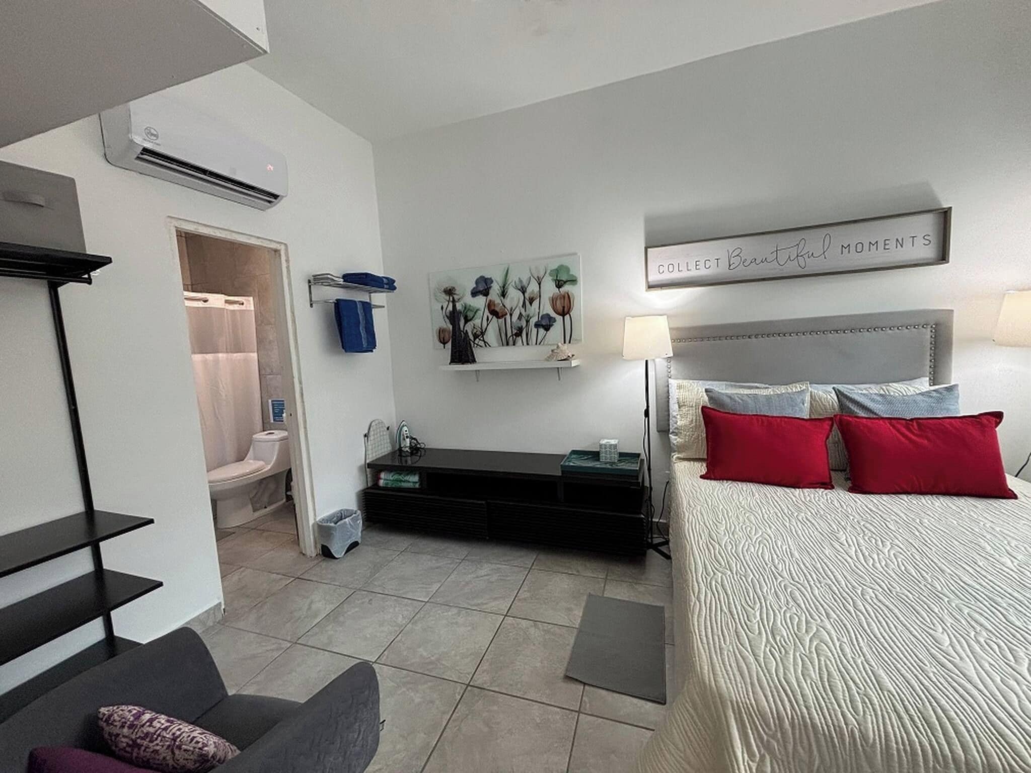 Ein Hotelzimmer mit Bett, Schreibtisch, Stuhl, Badezimmer und einem Wandbild.