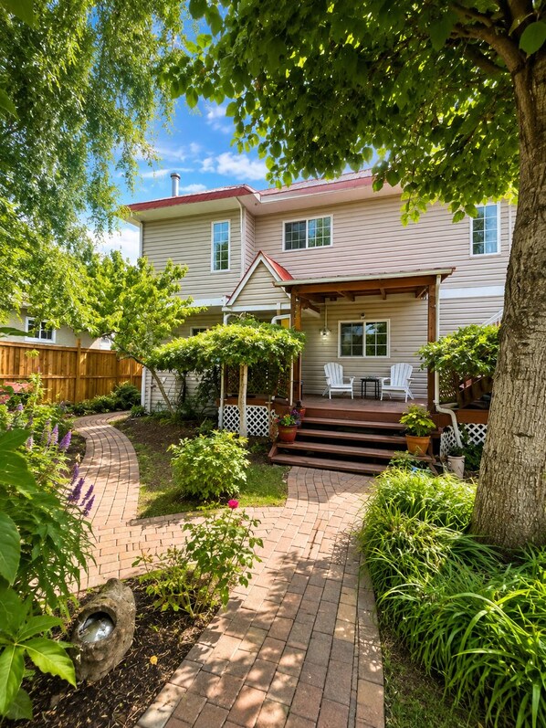 A two-story house with a covered porch and a brick pathway leading to the front door.