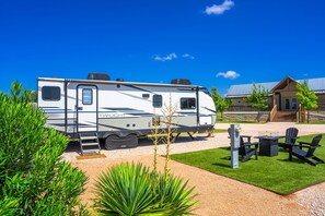 A recreational vehicle named 'TWILIGHT' parked in a well-maintained outdoor area with a picnic table and chairs, surrounded by greenery. - Glamping Getaway - On the 290 Wine Trail (Fredericksburg)