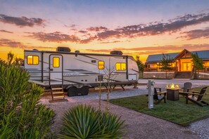 A recreational vehicle (RV) named 'TWILIGHT' parked in a campsite with a fire pit and outdoor seating area. - Glamping Getaway - On the 290 Wine Trail (Fredericksburg)