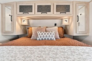 Une chambre à coucher comprenant un lit, deux tables de chevet et une tête de lit dotée d’un éclairage intégré.