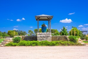 A gazebo with a stone base and a sign reading 'ArchRay RV Resort' under a clear blue sky. - Glamping Getaway - On the 290 Wine Trail (Fredericksburg)