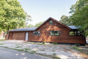 A single-story wooden house with a garage, two windows, and a small porch area. - Watts Bar Lake House Retreat (Kingston)