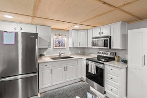 A modern kitchen with stainless steel appliances, white cabinetry, and a wooden ceiling. - Fabulous 3-bedroom 2 bath house with Central AC - 2 complete living spaces!  (Mansfield)