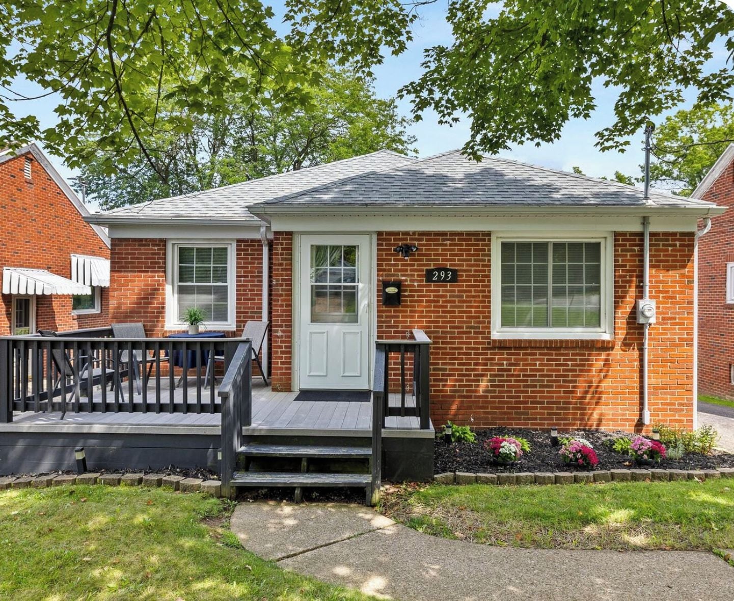 A single-story brick house with a front porch, a mailbox, and a number '293' on the door.