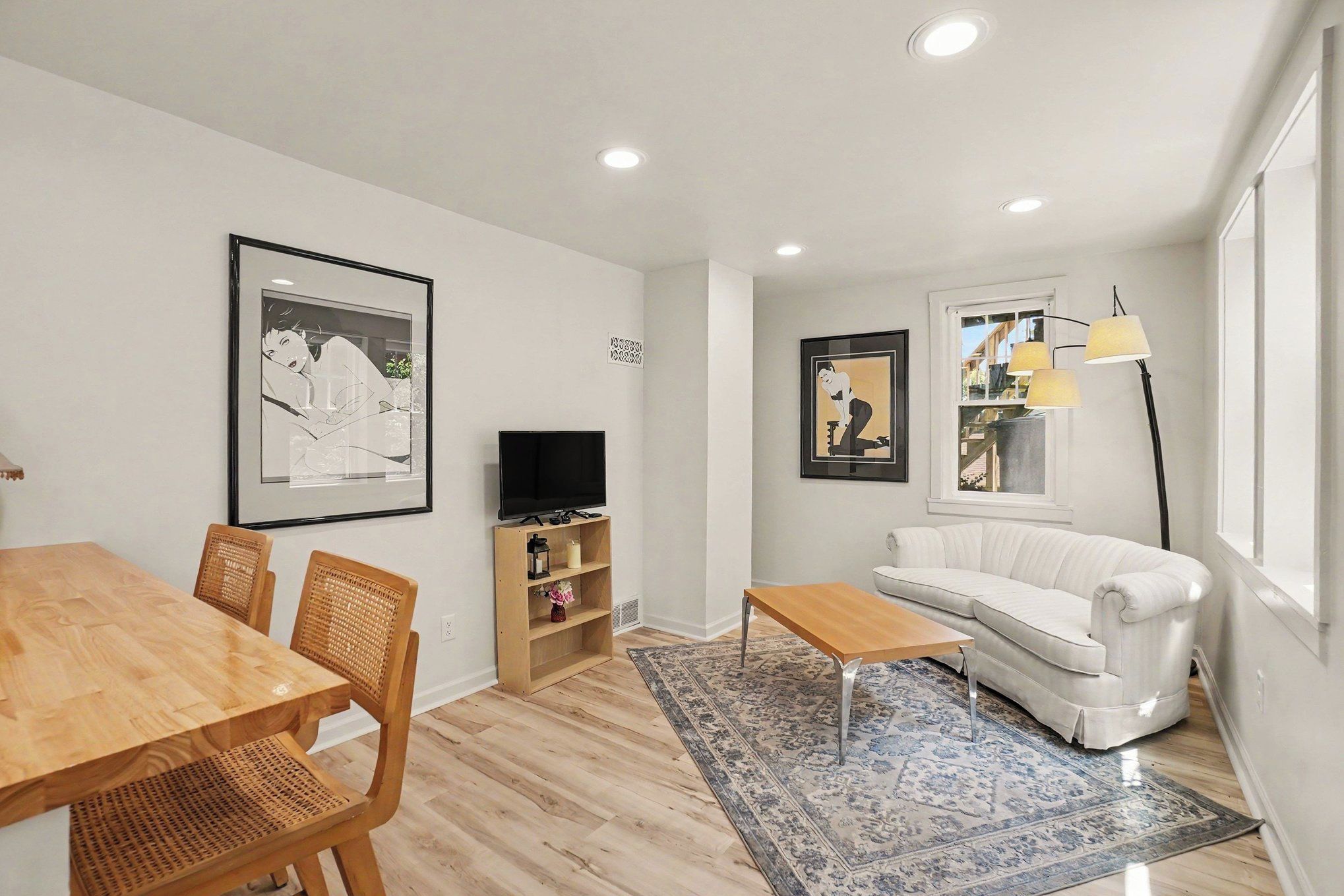 A modern living room with a sofa, a coffee table, a TV, and artwork on the walls.