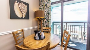A round wooden table with chairs, a lamp, and a tray with glasses, set against a wall with a large artwork. - Cozy Oceanfront Getaway! Landmark 640 for 6! (Myrtle Beach)