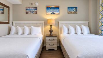 Ein Hotelzimmer mit zwei Betten, einem Nachttisch mit Lampe und Wandbildern.