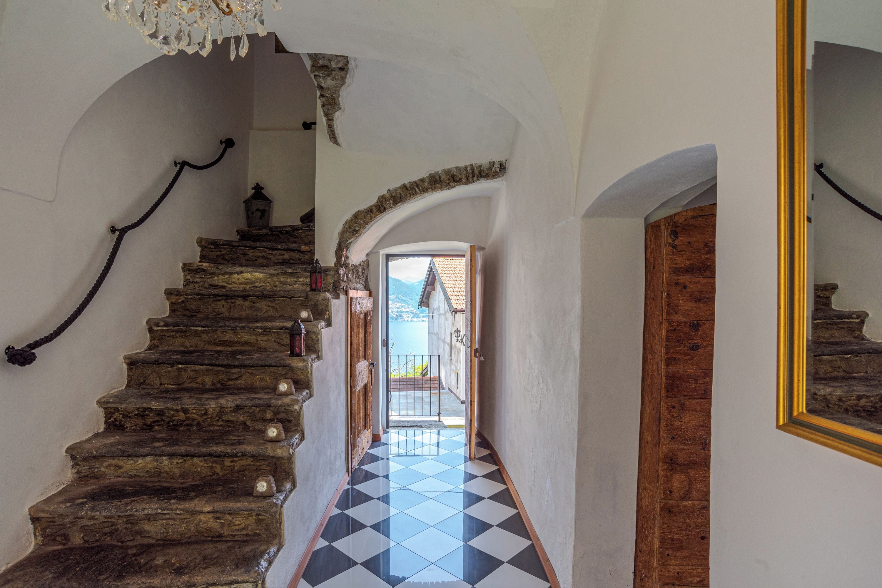 Una escalera con piso a cuadros que lleva a un balcón con vistas a una montaña.