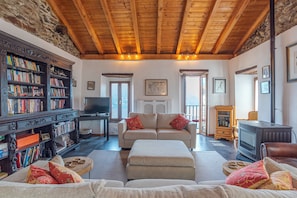 A cozy living room with a fireplace, a television, a sofa, and a bookshelf. - Casa Rustica, Rezzonico, Italy (Rezzonico)