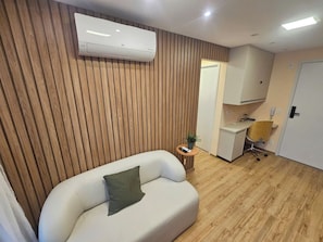 Een moderne kamer met een witte bank, een klein rond tafeltje met een plant en een bureau met een stoel.