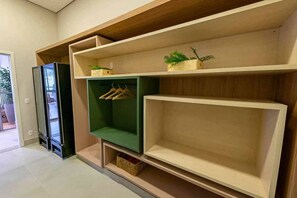 A room with a built-in shelving unit, a hanging rack, and a small plant on the shelf. - Apartamento em Moema com varanda e vista da cidade (São Paulo)
