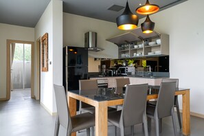A modern kitchen with a central island, black appliances, and a dining area with a wooden table and chairs.