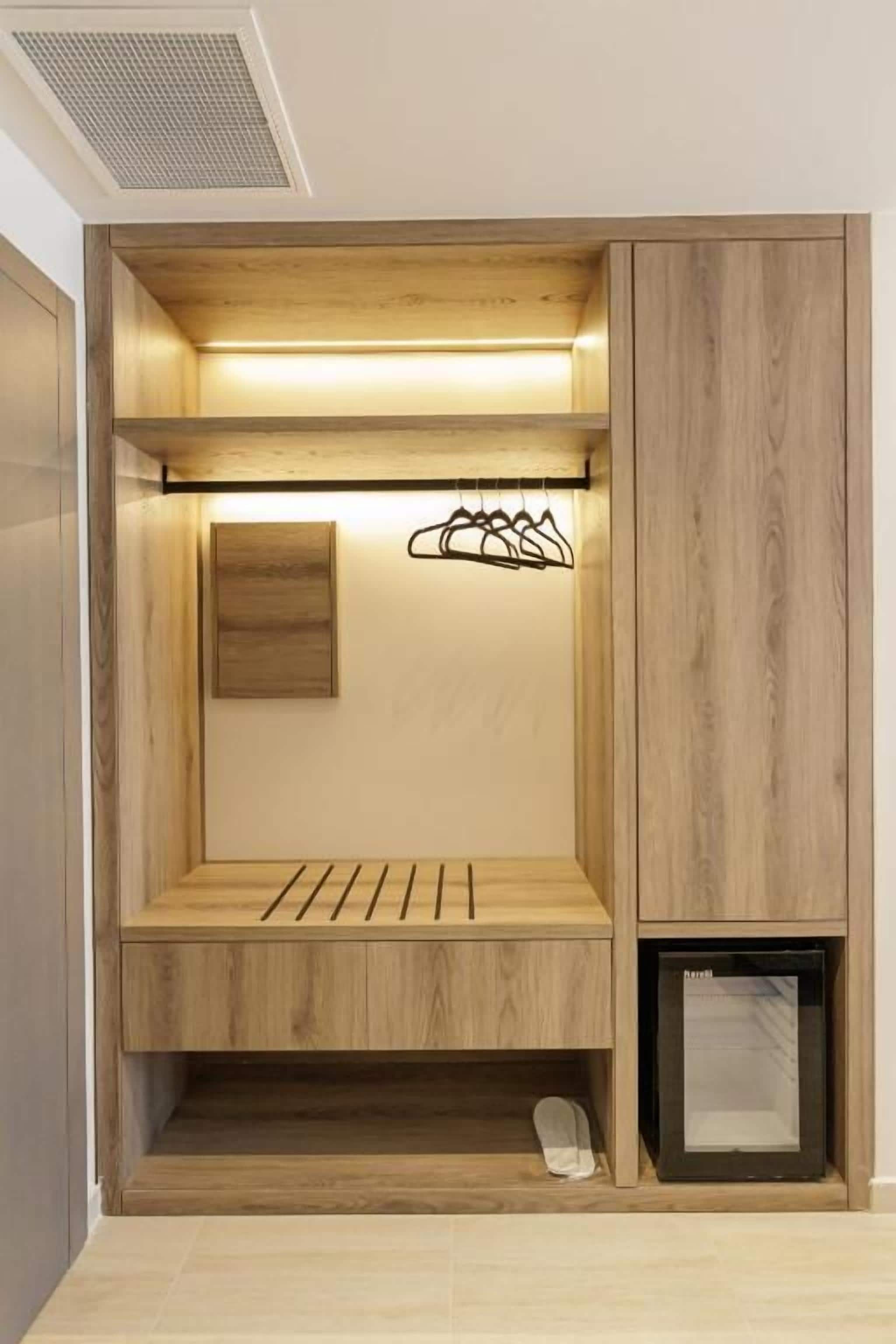 Un armario con estantes de madera, una barra para colgar ropa y un zapatero.