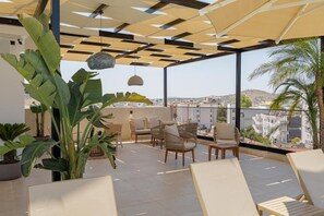 Una terrazza sul tetto con posti a sedere all'aperto, vista sulla città e piante in vaso.