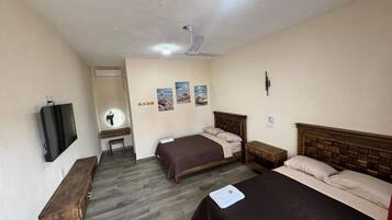 A hotel room with two beds, a TV, a ceiling fan, and a small desk with a chair.