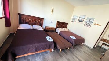Habitación de hotel con dos camas, cabecero de madera, mesita de noche y una pared decorada con motivos náuticos.