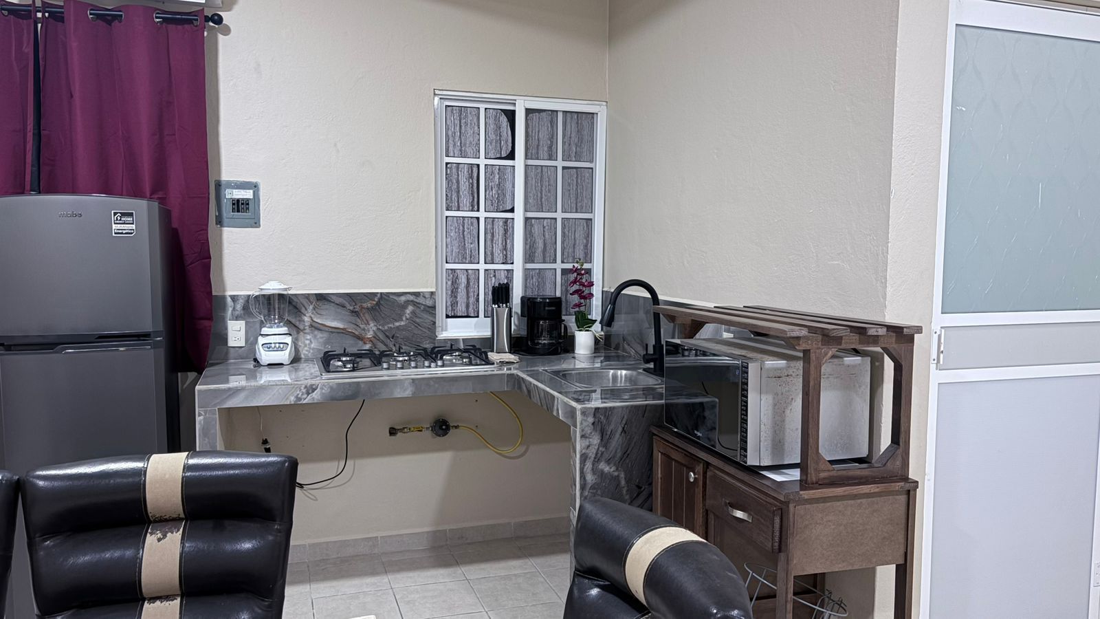 A compact kitchen with a refrigerator, stove, sink, and microwave.