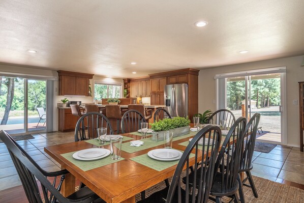 A spacious dining area with a wooden table, chairs, and a view of the outdoors through large sliding doors.