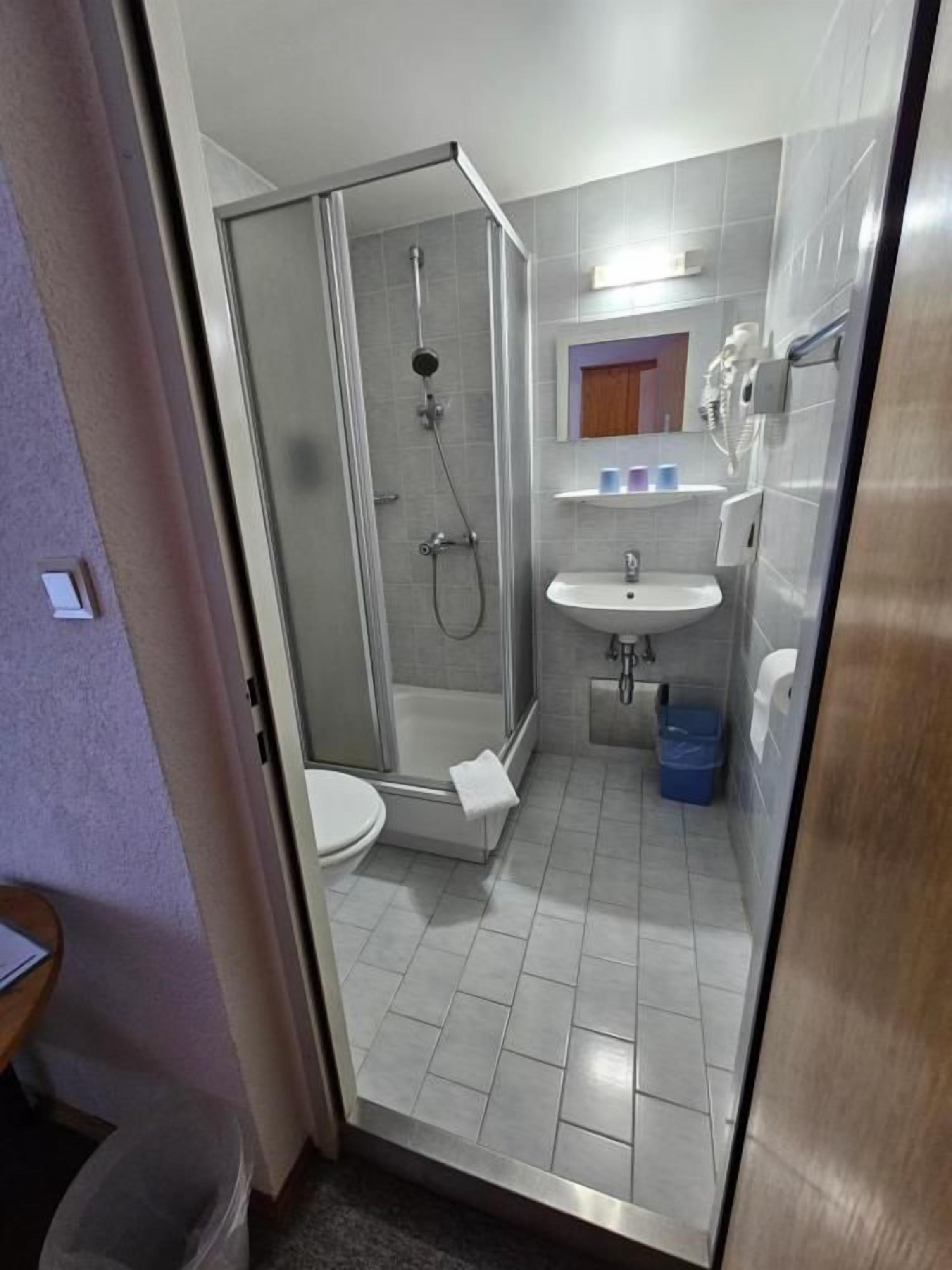 A bathroom with a glass-enclosed shower, a sink, and a toilet.