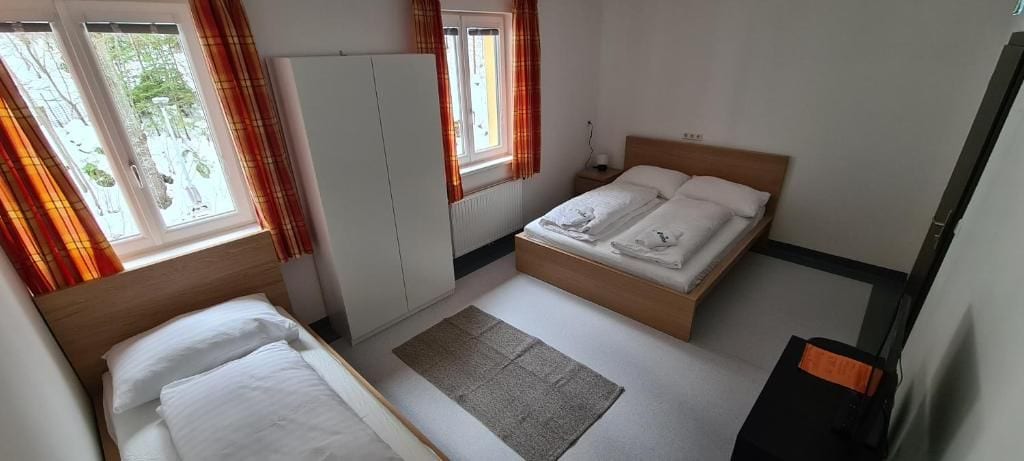 Un dormitorio con dos camas, un armario, un radiador y una ventana con cortinas.